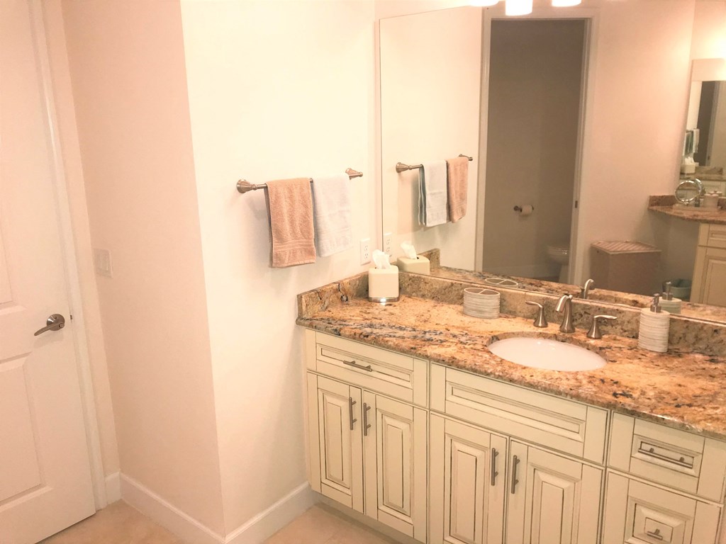 a bathroom with white cabinets and a sink and a mirror