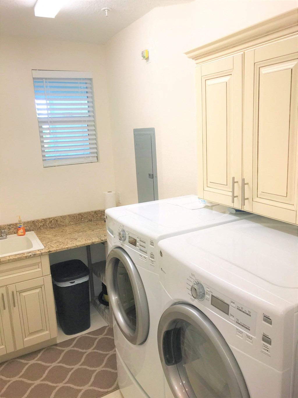 a white washer and dryer in a laundry room with white cabinets