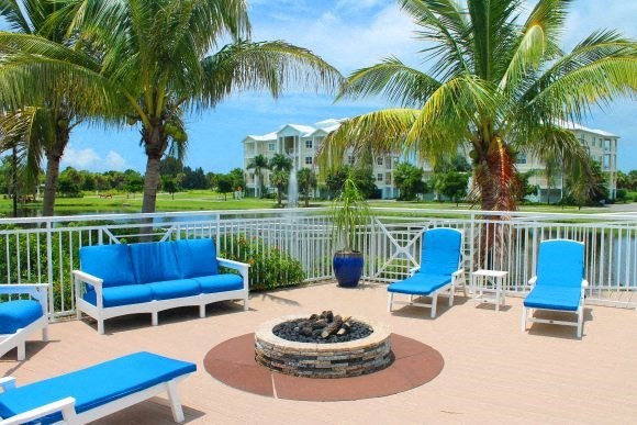 a patio with blue chairs and a fire pit