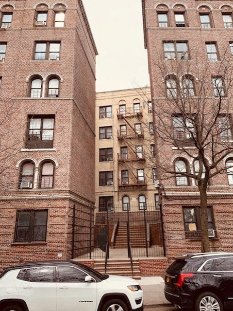 a white car parked in front of a tall brick building