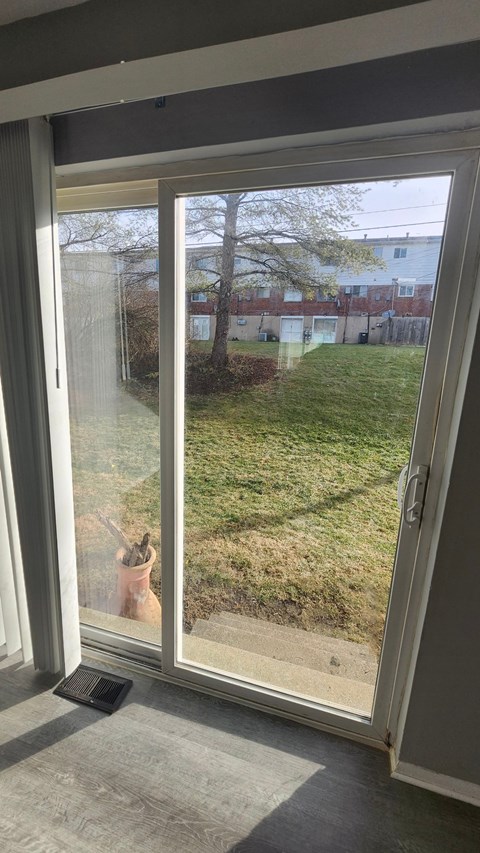 A person is standing in a doorway looking out at a grassy area.