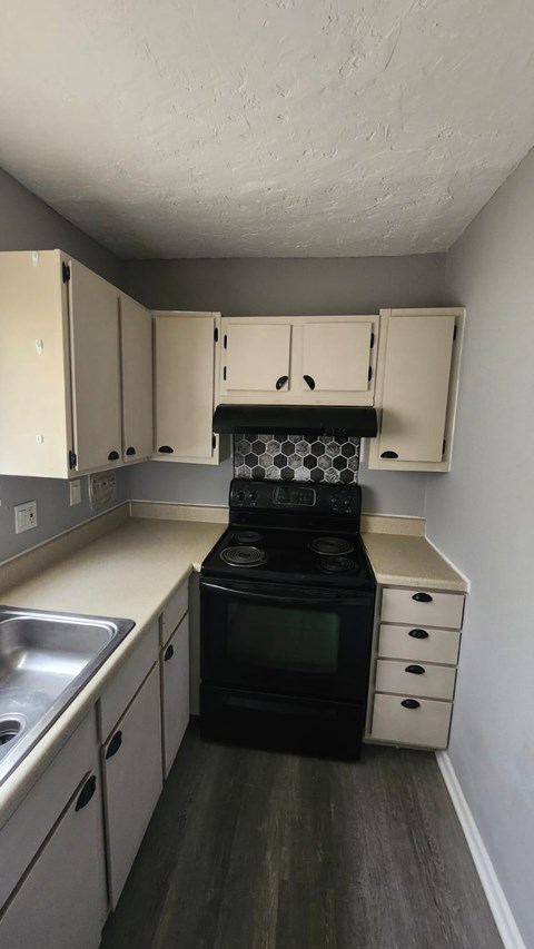 A kitchen with a black stove top oven and white cabinets.