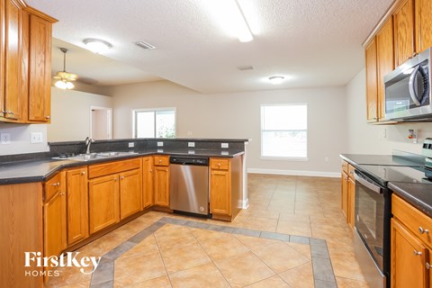 a kitchen with wooden cabinets and black counter tops and a stainless steel dishwasher