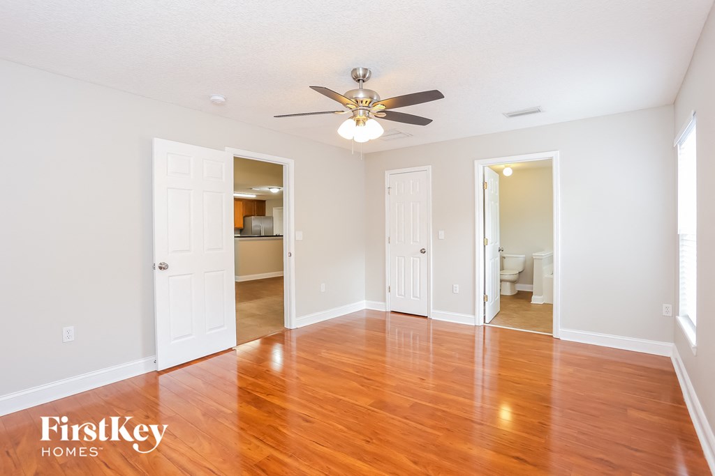 an empty living room with wood floors and a ceiling fan