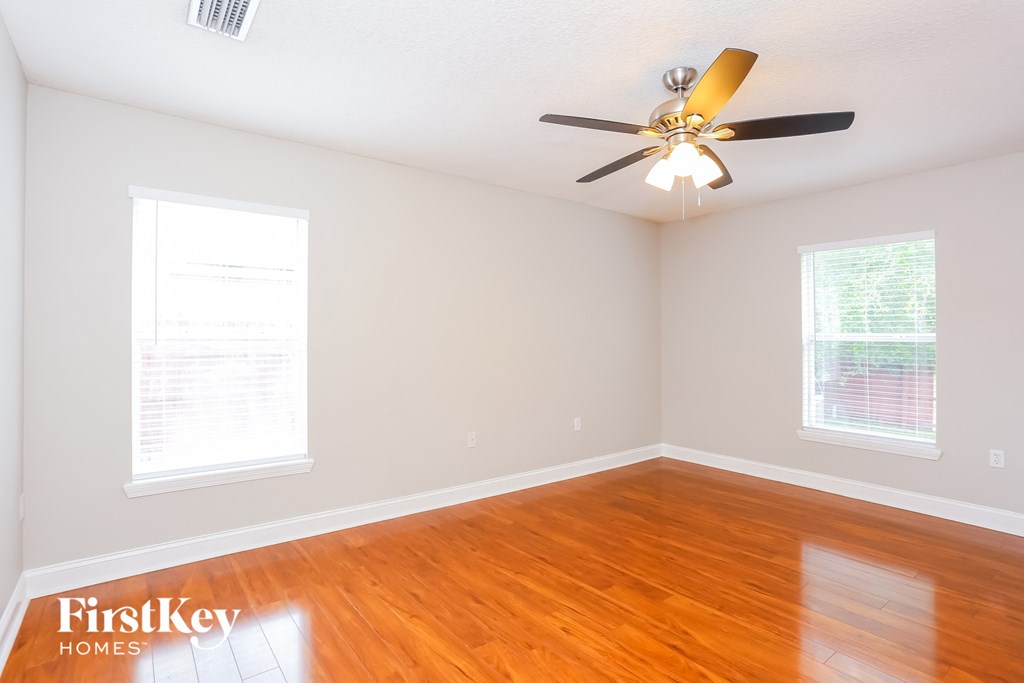a bedroom with wood floors and a ceiling fan