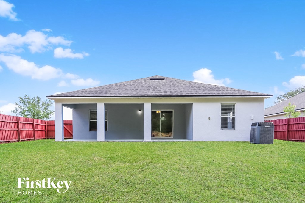 a small white house with a grass yard and a red fence