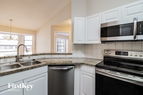 a kitchen with white cabinets and black appliances