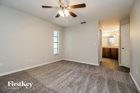 the spacious living room with carpet and ceiling fan