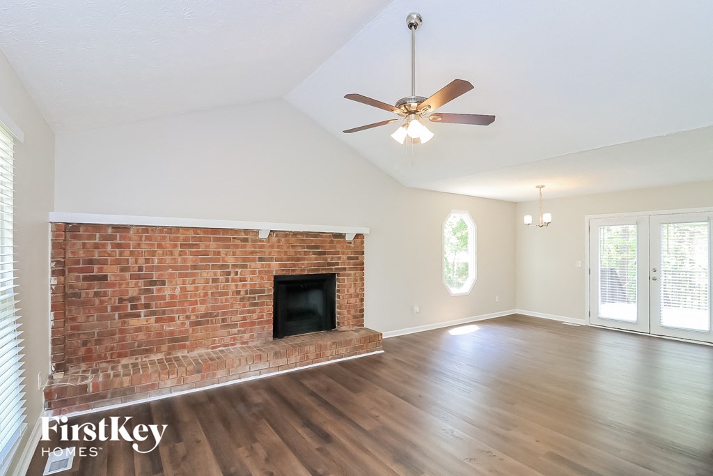 A room with a brick fireplace and wooden floors.