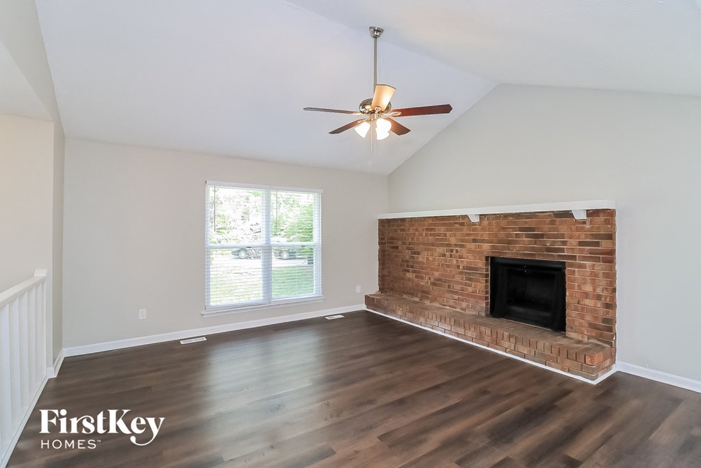 A room with a brick fireplace and wooden floors.