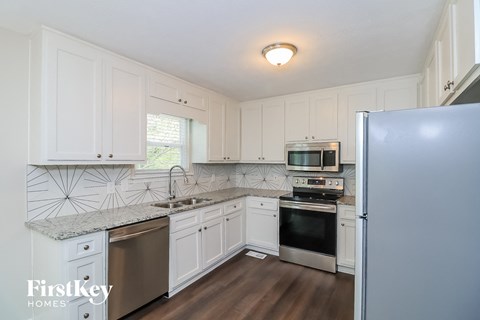 A kitchen with white cabinets and a stainless steel refrigerator.