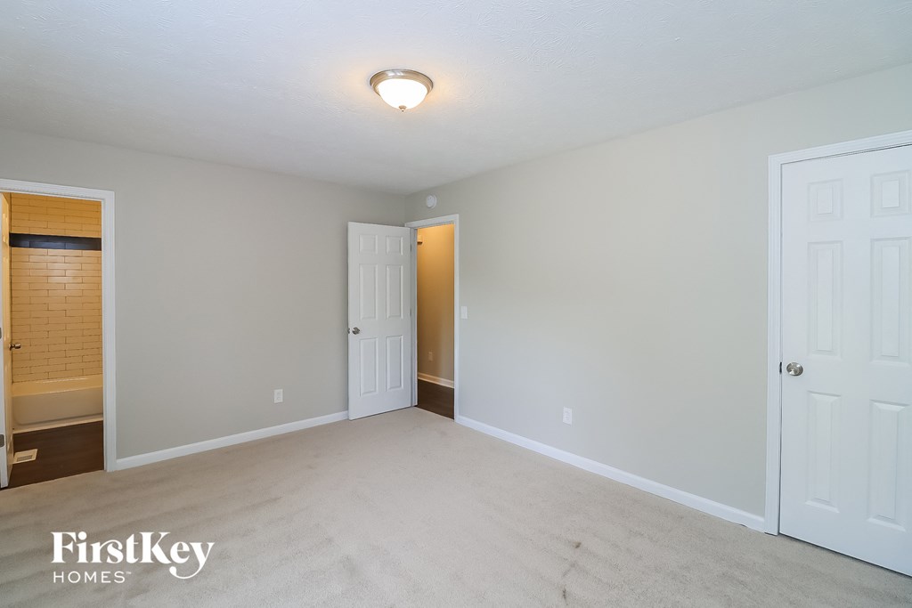 A spacious room with a carpeted floor and two doors.