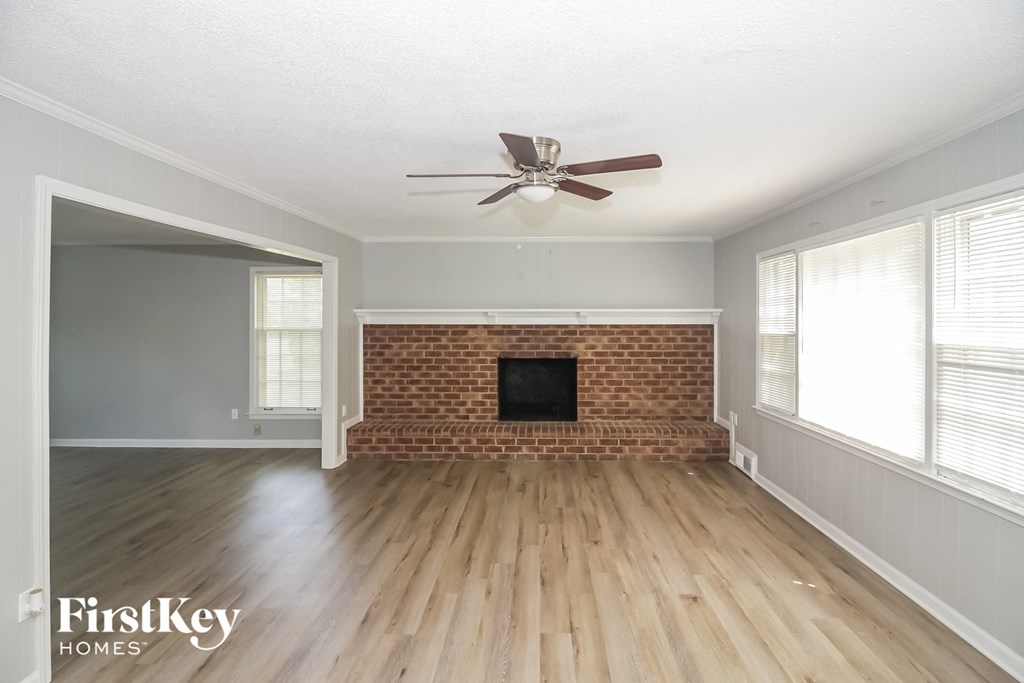 A room with a brick fireplace and wooden floors.