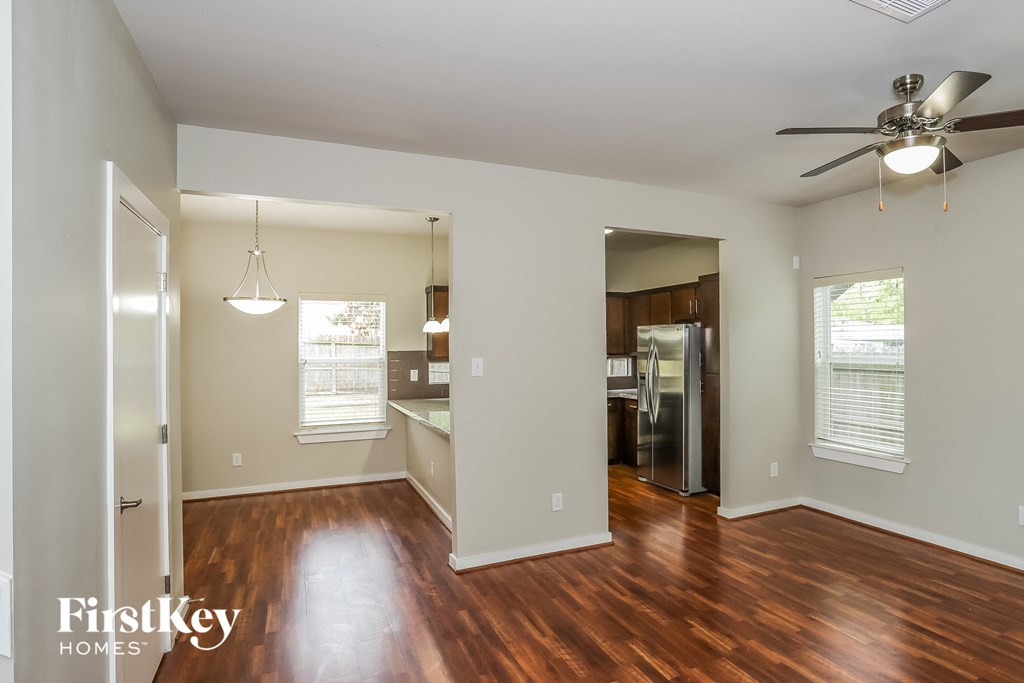 A spacious room with wooden floors and a ceiling fan.
