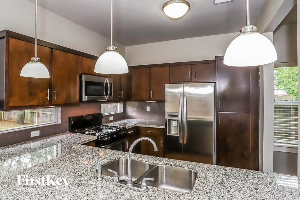 A kitchen with a granite countertop and stainless steel appliances.