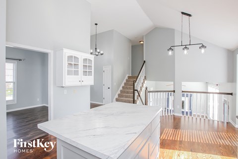 an open kitchen with a marble counter top and a staircase