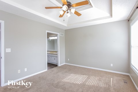 a living room with a ceiling fan and a carpet