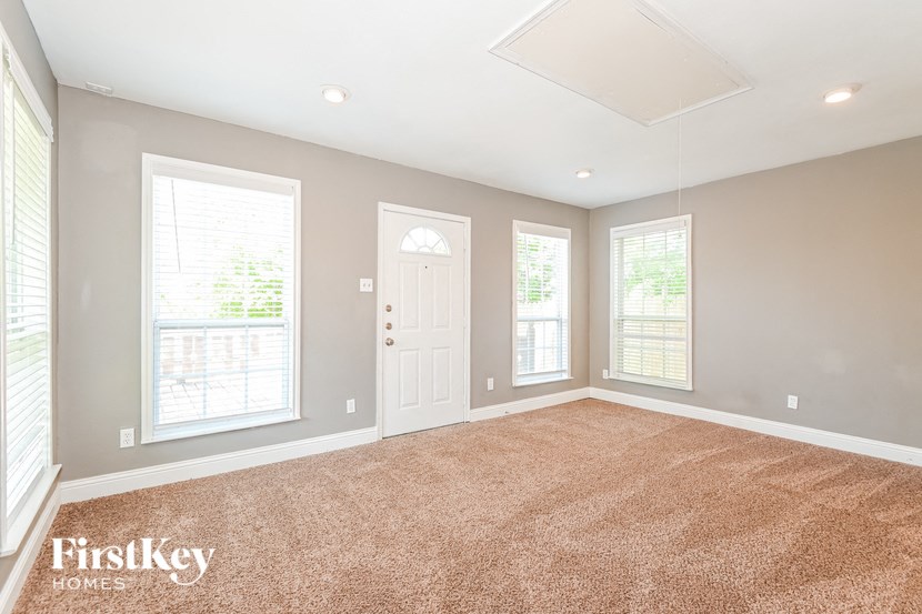 an empty living room with three windows and a white door