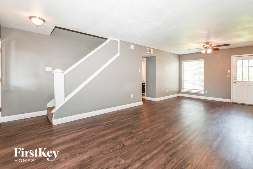 an empty living room with hardwood floors and a ceiling fan