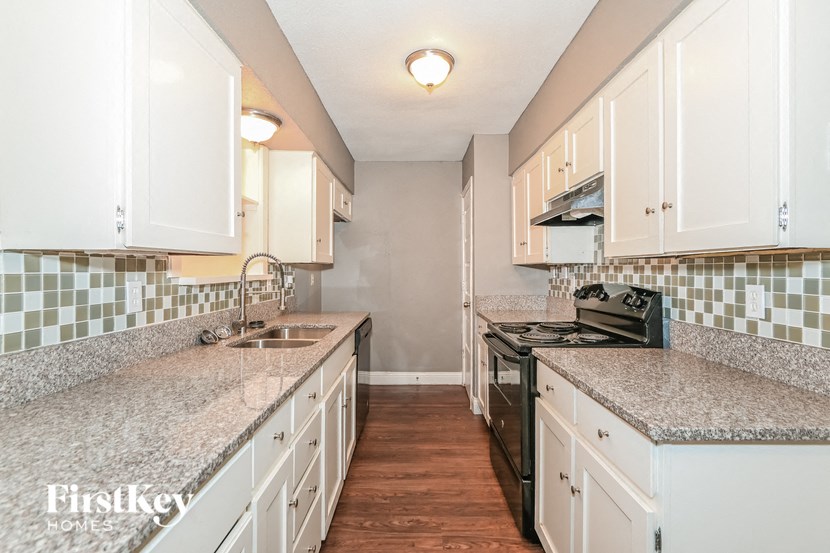 a kitchen with white cabinets and granite counter tops