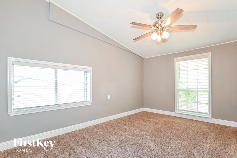 an empty bedroom with a ceiling fan and a window