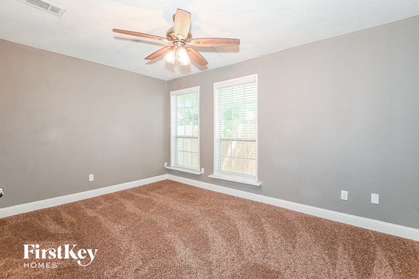 an empty living room with a ceiling fan