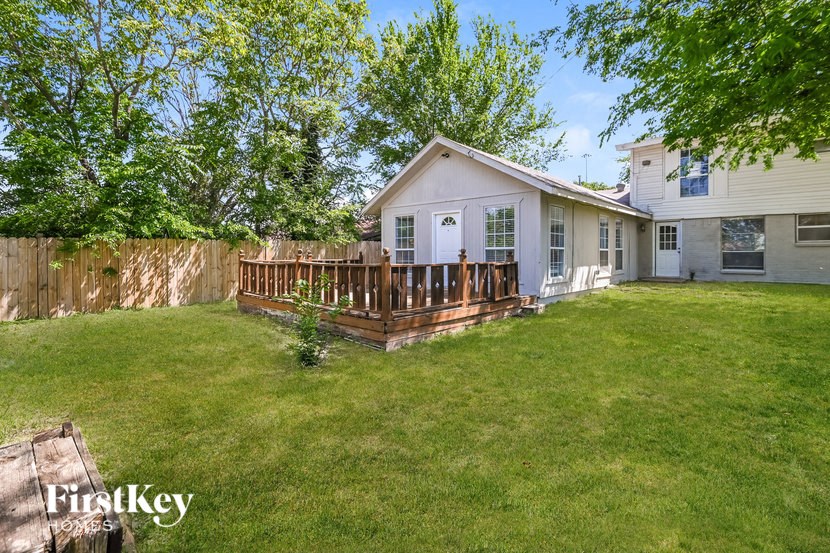a backyard with a white house and a wooden deck