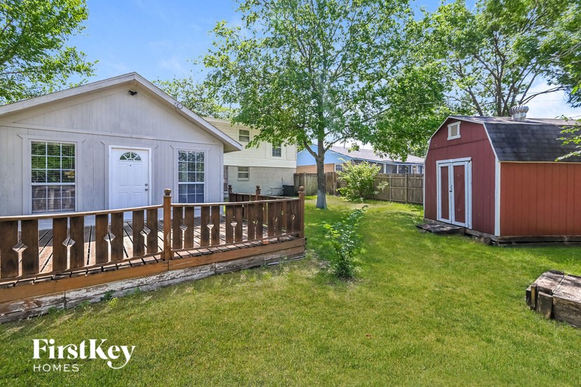 a cottage with a red barn and a yard with a deck