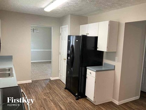 A black refrigerator in a kitchen with white cabinets.