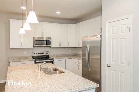 a kitchen with white cabinets and granite counter tops and a stainless steel refrigerator