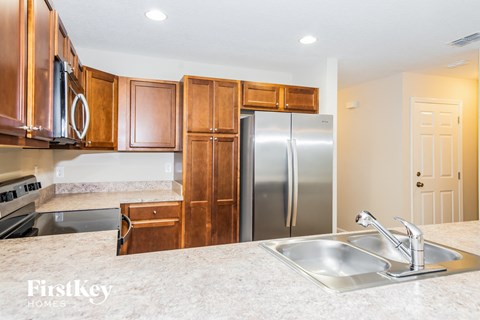 A kitchen with wooden cabinets and a stainless steel refrigerator.
