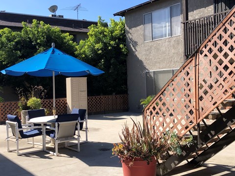 a patio with a blue umbrella and a table with chairs
