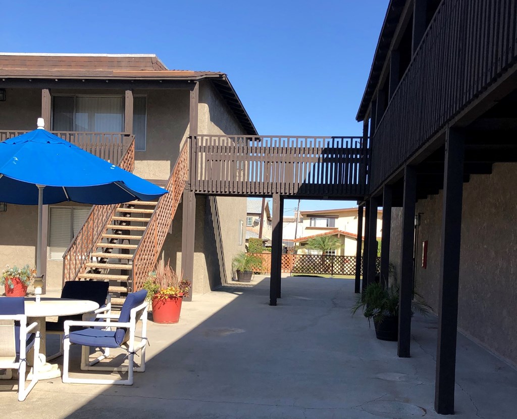 a patio outside a building with tables and chairs and an umbrella
