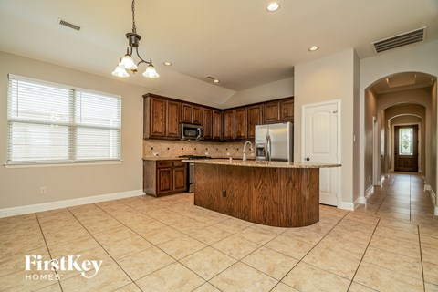 A kitchen with wooden cabinets and a tiled floor.