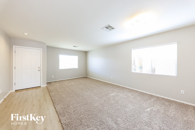 a spacious living room with a white door and a carpeted floor