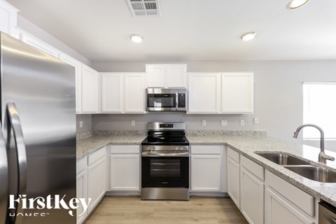 A kitchen with a stainless steel refrigerator and white cabinets.