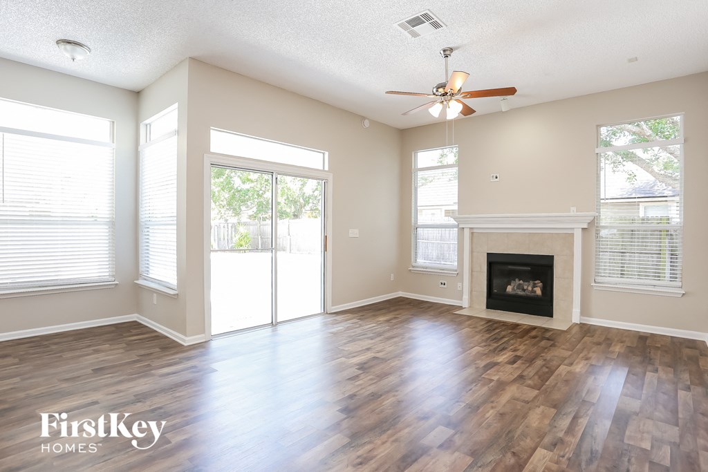 A spacious living room with wood flooring and a fireplace.