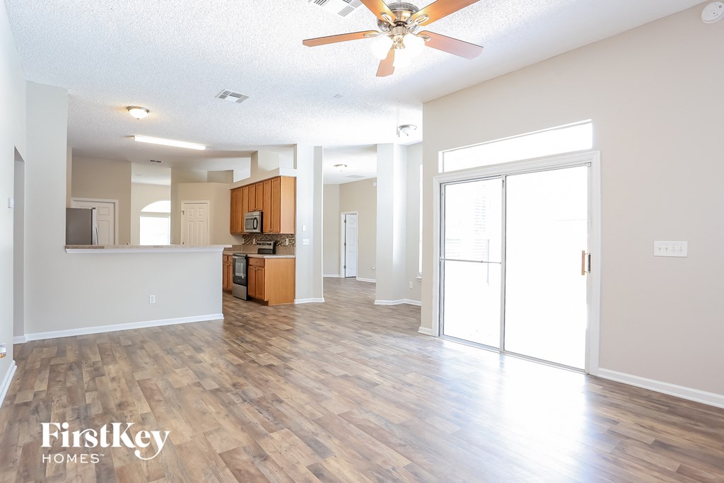 A spacious living room with wooden flooring and a ceiling fan.