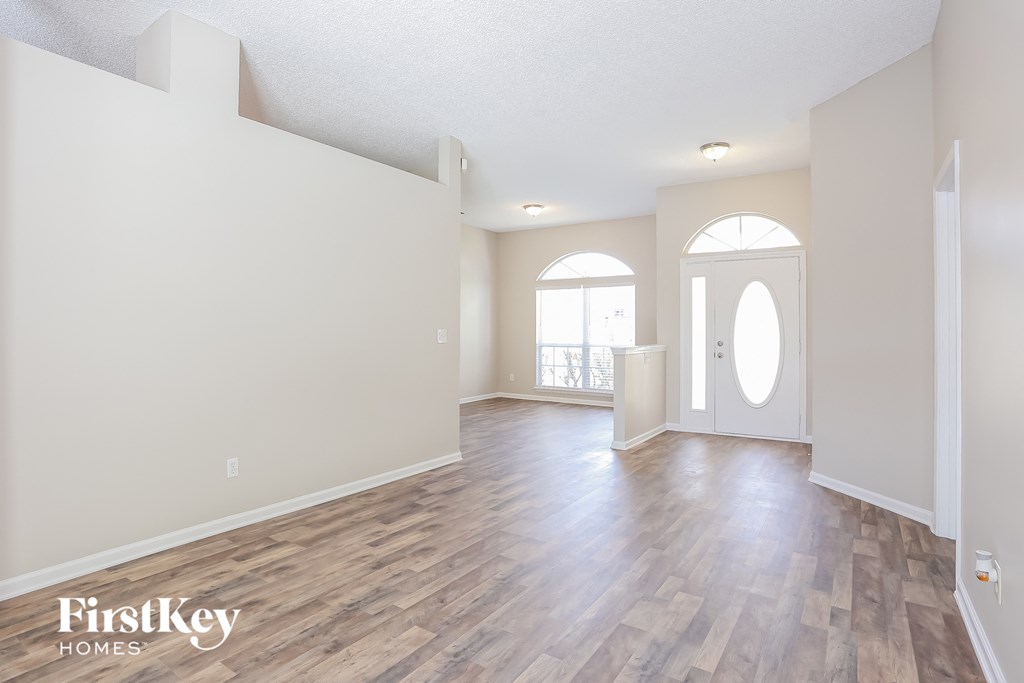 A spacious room with wooden flooring and a large window.