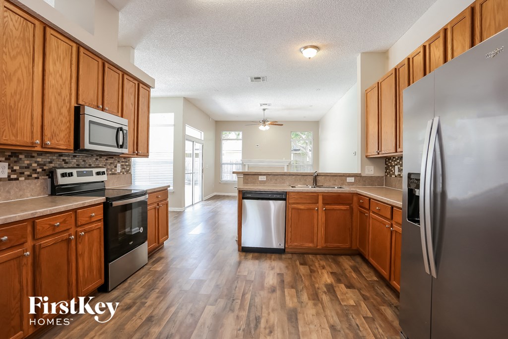A kitchen with wooden cabinets and a stainless steel refrigerator.