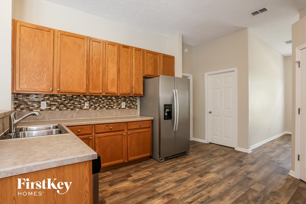 A kitchen with wooden cabinets and a stainless steel refrigerator.