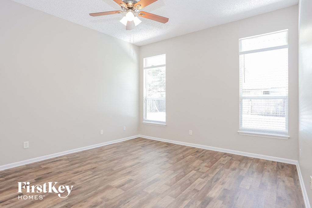 A room with a ceiling fan and wooden flooring.