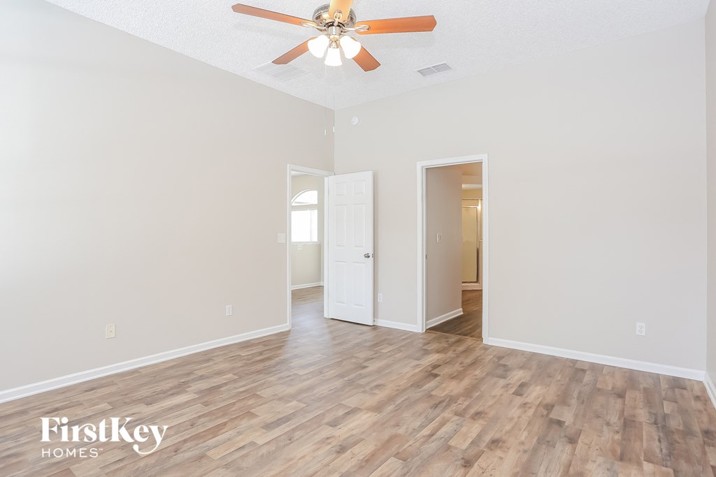 A room with a ceiling fan and wooden flooring.