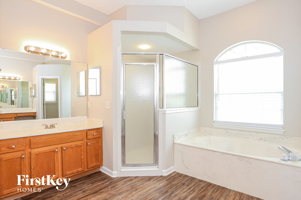 A bathroom with a wooden vanity and a walk-in shower.