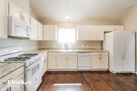 A kitchen with white appliances and cabinets.