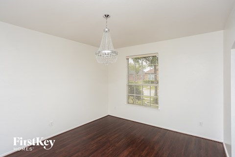 a bedroom with white walls and wood floors and a window