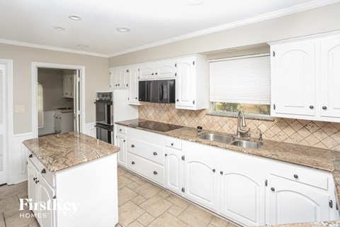 a white kitchen with granite counter tops and white cabinets