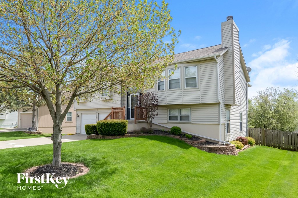 a white house with a lawn and a tree in front of it