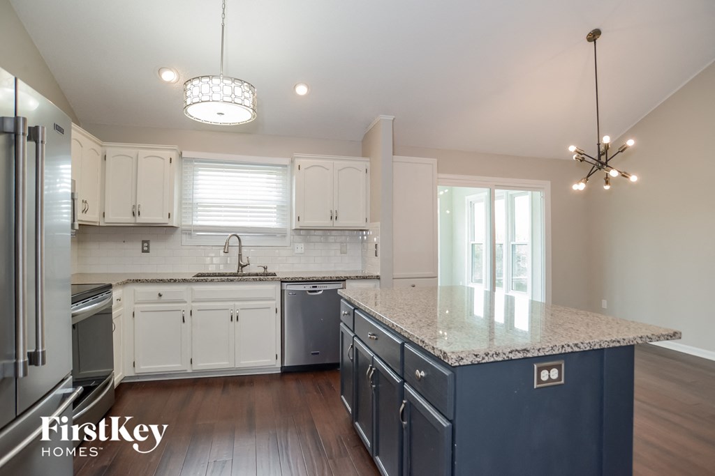 a kitchen with white cabinets and a marble counter top