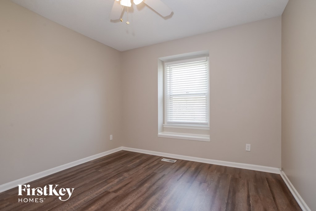 the second bedroom with hardwood flooring and a window